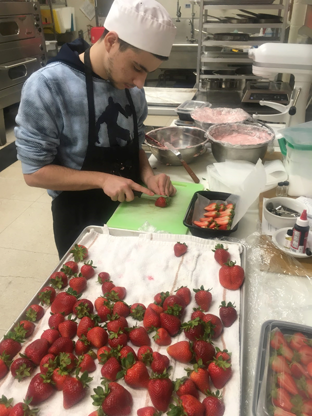 Student cutting strawberries for dessert. Open Gallery